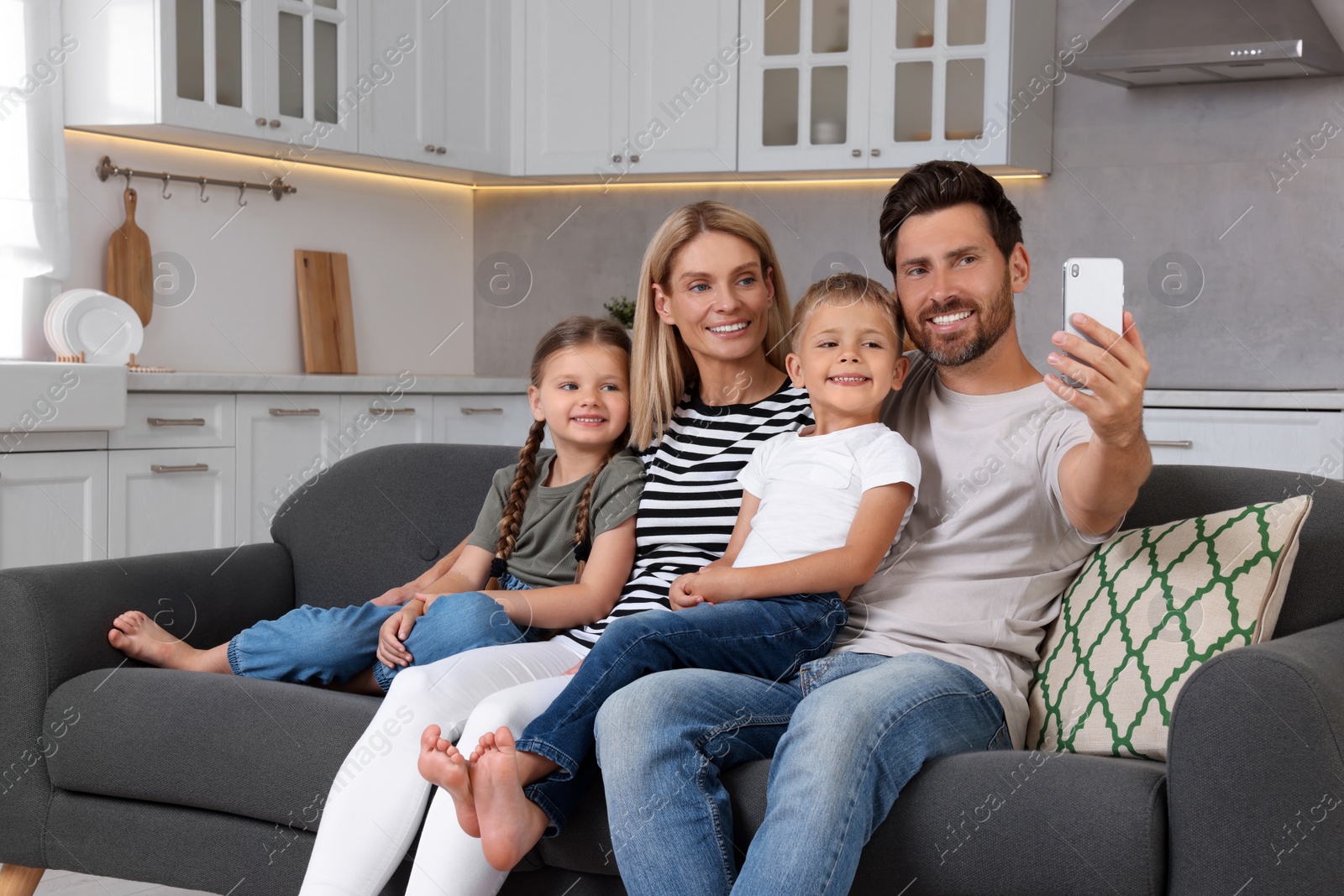 Photo of Happy family taking selfie together on sofa at home