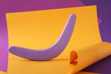 Photo of Creative composition with lilac wooden boomerang on color background