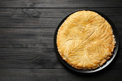 Traditional galette des rois on black wooden table, top view. Space for text