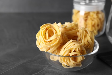 Photo of Tagliatelle pasta in bowl on black table, closeup. Space for text