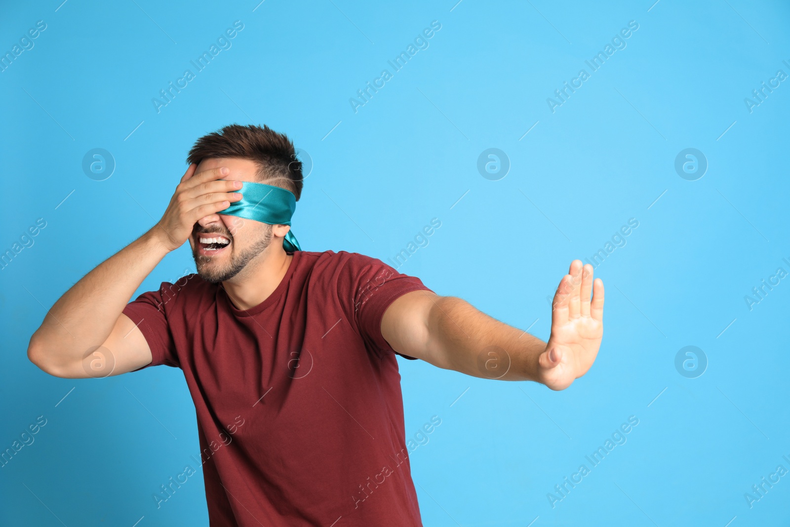 Photo of Young man with blindfold on blue background