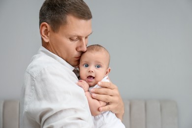 Photo of Father holding his cute baby at home, space for text