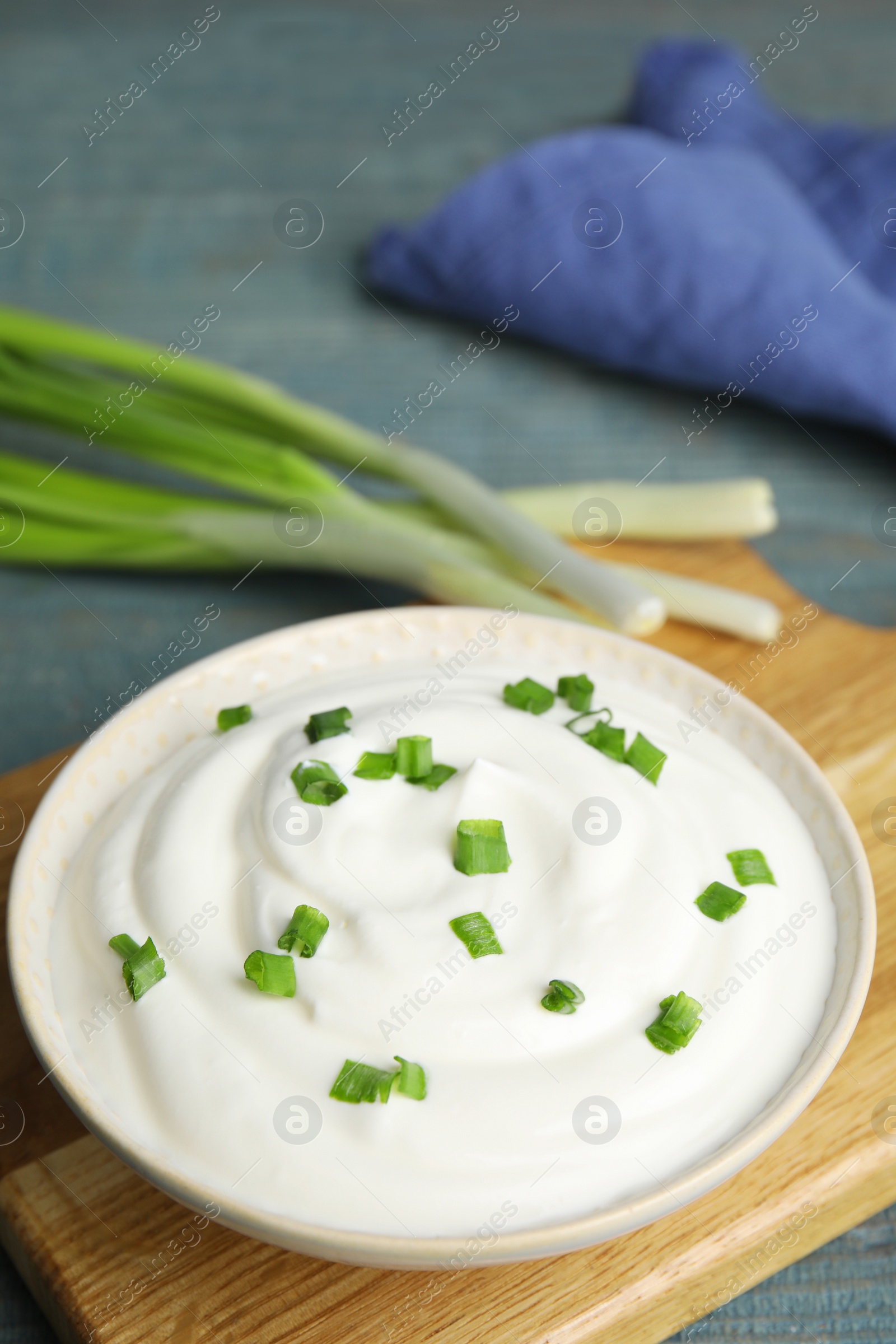 Photo of Fresh sour cream with onion on wooden board, closeup