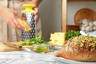 Photo of Tasty homemade garlic bread with cheese  and blurred woman on background. Space for text