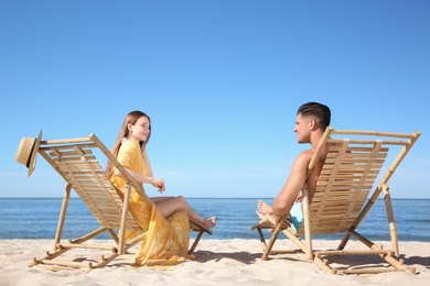 Woman and her boyfriend on deck chairs at beach. Happy couple