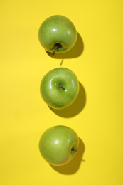 Tasty green apples on yellow background, flat lay
