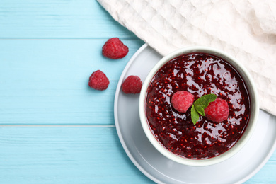 Delicious jam and fresh raspberries on light blue wooden table, flat lay