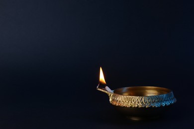 Photo of Lit diya lamp on black background, space for text. Diwali celebration