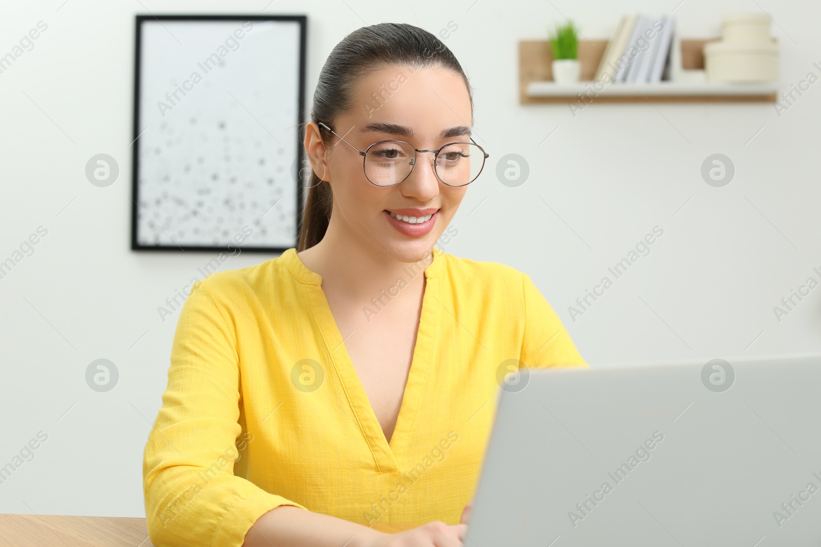 Photo of Home workplace. Happy woman working on laptop indoors