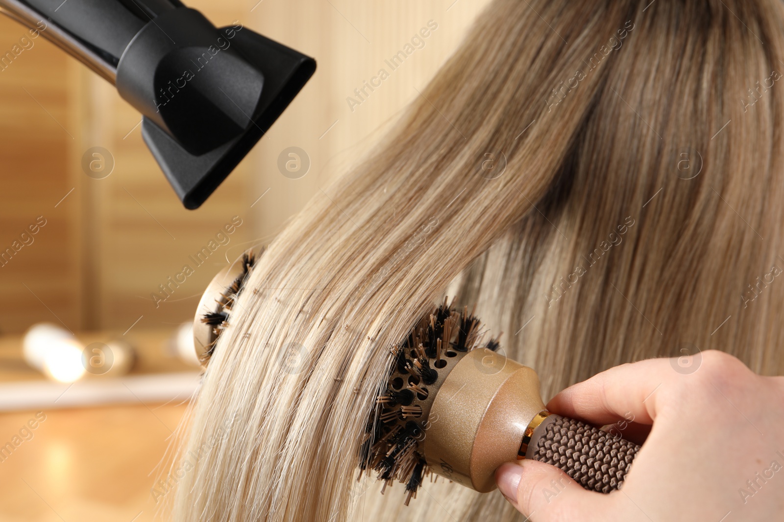 Photo of Hairdresser blow drying client's hair in salon, closeup