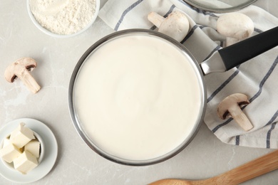 Photo of Flat lay composition with delicious creamy sauce in pan on marble table
