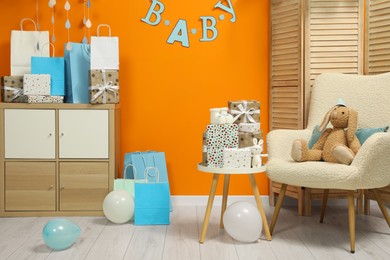 Photo of Baby shower party. Festive decor, booties, toys and gift boxes in stylish room