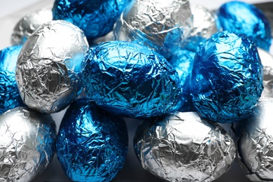 Photo of Chocolate eggs wrapped in blue and silver foil as background, closeup