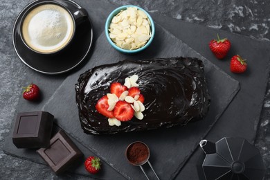 Delicious chocolate sponge cake, coffee and ingredients on black table, flat lay