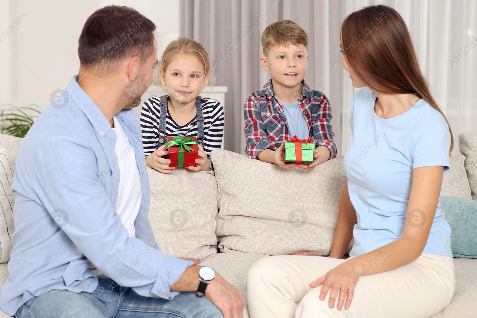 Photo of Little children presenting their parents with gifts at home