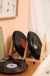 Photo of Vinyl records and player on white wooden drawer dresser near indoors