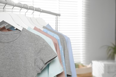 Photo of Different apparel hanging on clothes rack indoors, closeup. Space for text