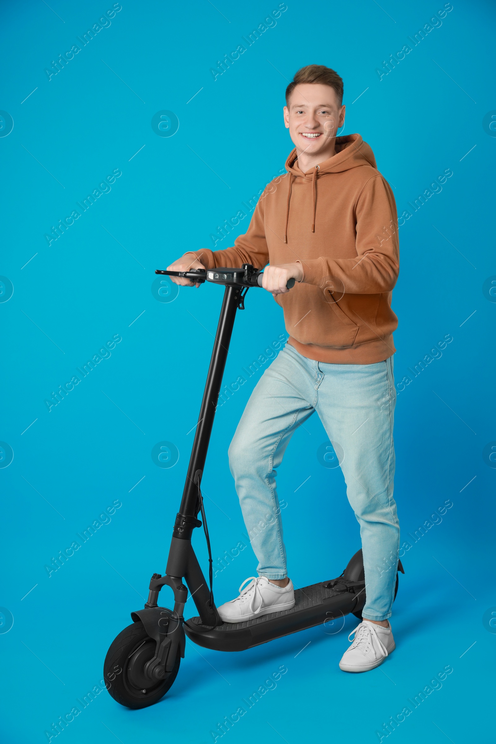 Photo of Happy man with modern electric kick scooter on light blue background