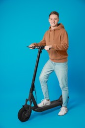 Photo of Happy man with modern electric kick scooter on light blue background