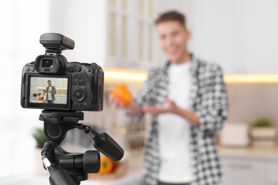 Food blogger recording video in kitchen, focus on camera