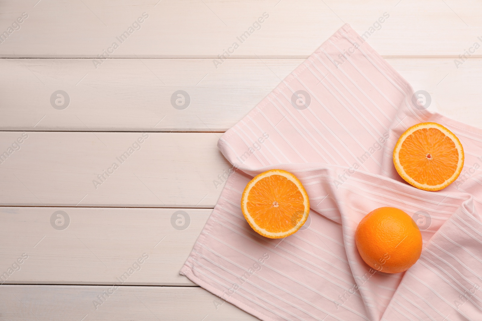 Photo of Pink kitchen towel with oranges on white wooden table, flat lay. Space for text