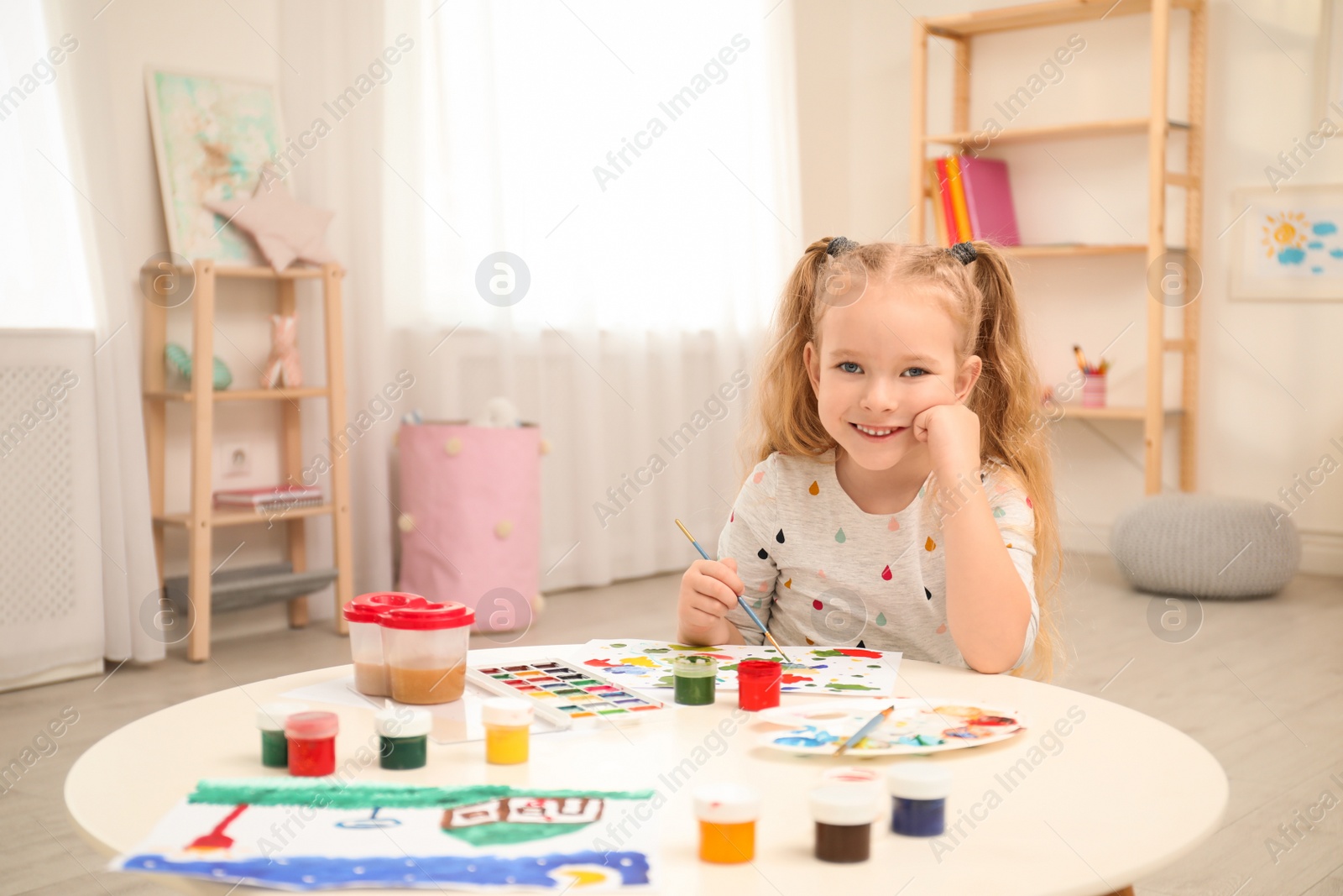 Photo of Cute little child painting at table in room