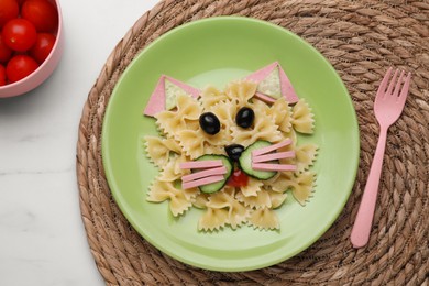 Creative serving for kids. Plate with cute cat made of tasty pasta, vegetables and sausage on table, flat lay