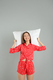 Young woman with pillow on grey background