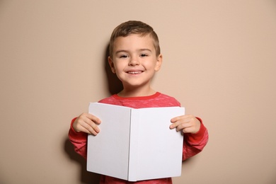 Photo of Cute little boy with book on color background