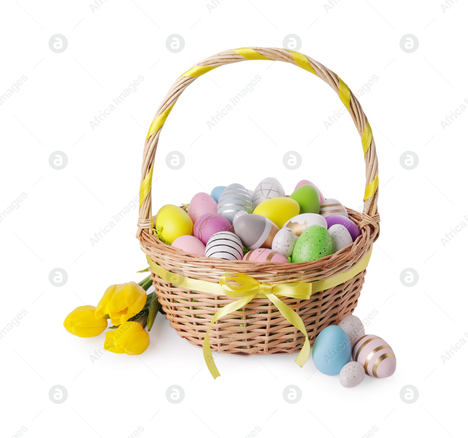 Photo of Wicker basket with beautifully painted Easter eggs and tulips isolated on white