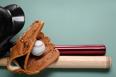 Baseball glove, bats, ball and batting helmet on pale green background, flat lay. Space for text