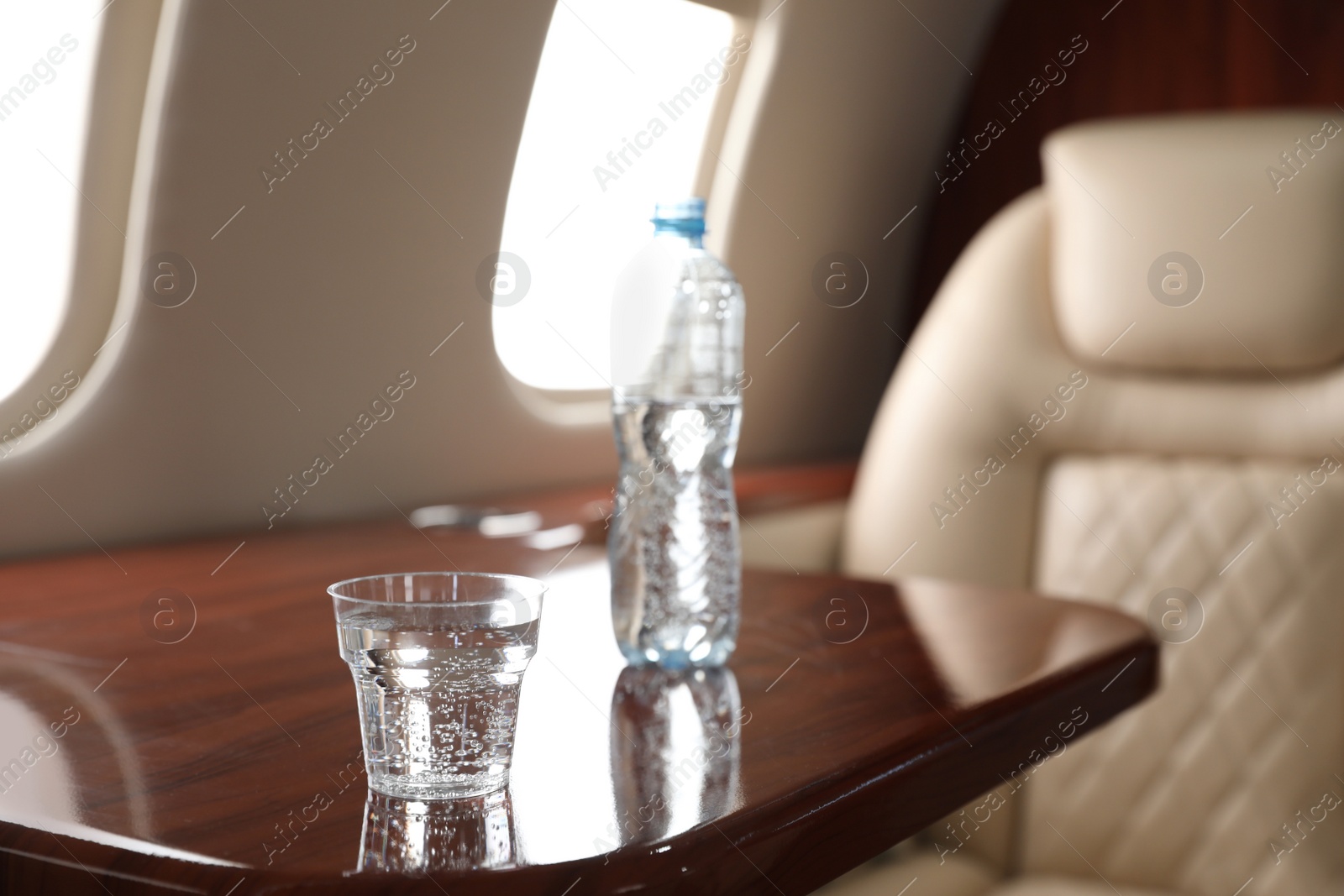 Image of Glass and bottle with water on plane. Comfortable flight