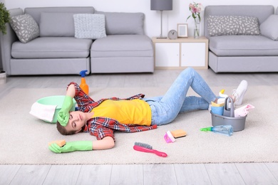 Tired woman sleeping on floor after cleaning carpet at home