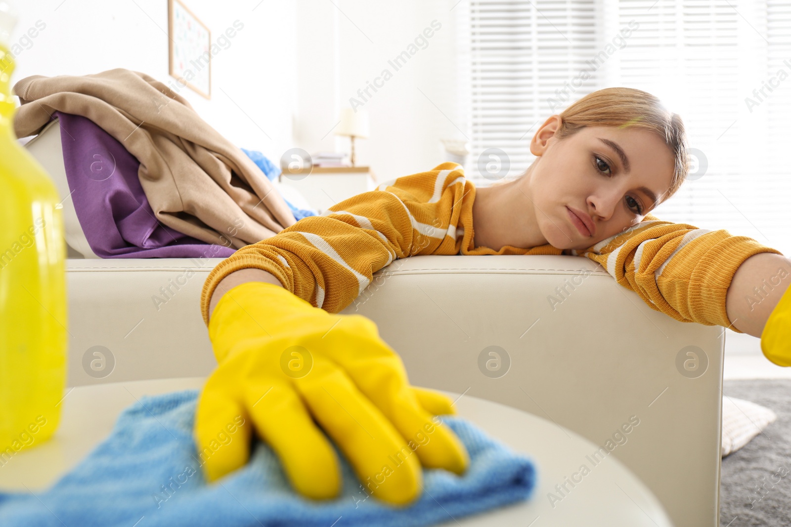 Photo of Lazy young woman wiping table at home. Cleaning and housework