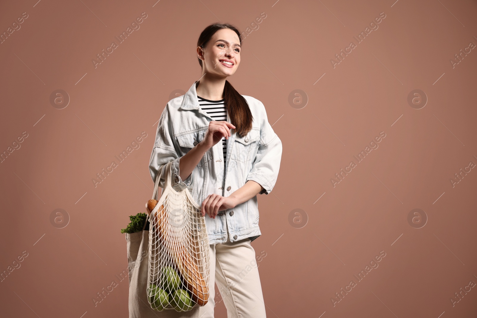 Photo of Woman with eco bags full of products on pink background