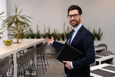 Happy real estate agent with leather portfolio in office