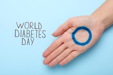 Photo of Woman showing palm with drawn blue circle near text World Diabetes Day on color background, top view