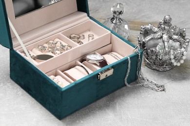 Jewelry box with many different accessories, perfume and decor on light grey table