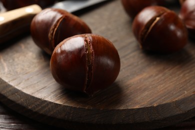 Photo of Roasted edible sweet chestnuts on table, closeup