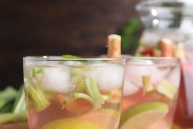Photo of Glasses of tasty rhubarb cocktail with citrus fruits on blurred background, closeup