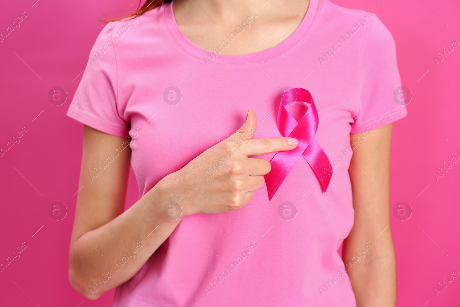 Photo of Woman with pink ribbon on color background, closeup. Breast cancer awareness