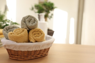 Photo of Basket with towels on wooden table indoors, space for text. Spa time