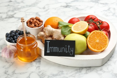 Card with word Immunity and fresh products on light marble background