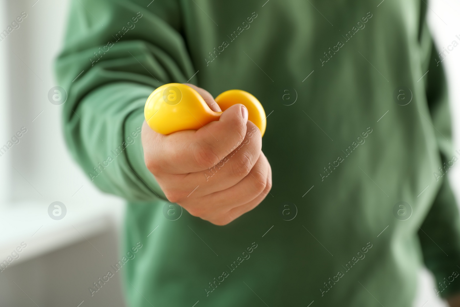 Photo of Man squeezing yellow stress ball indoors, closeup