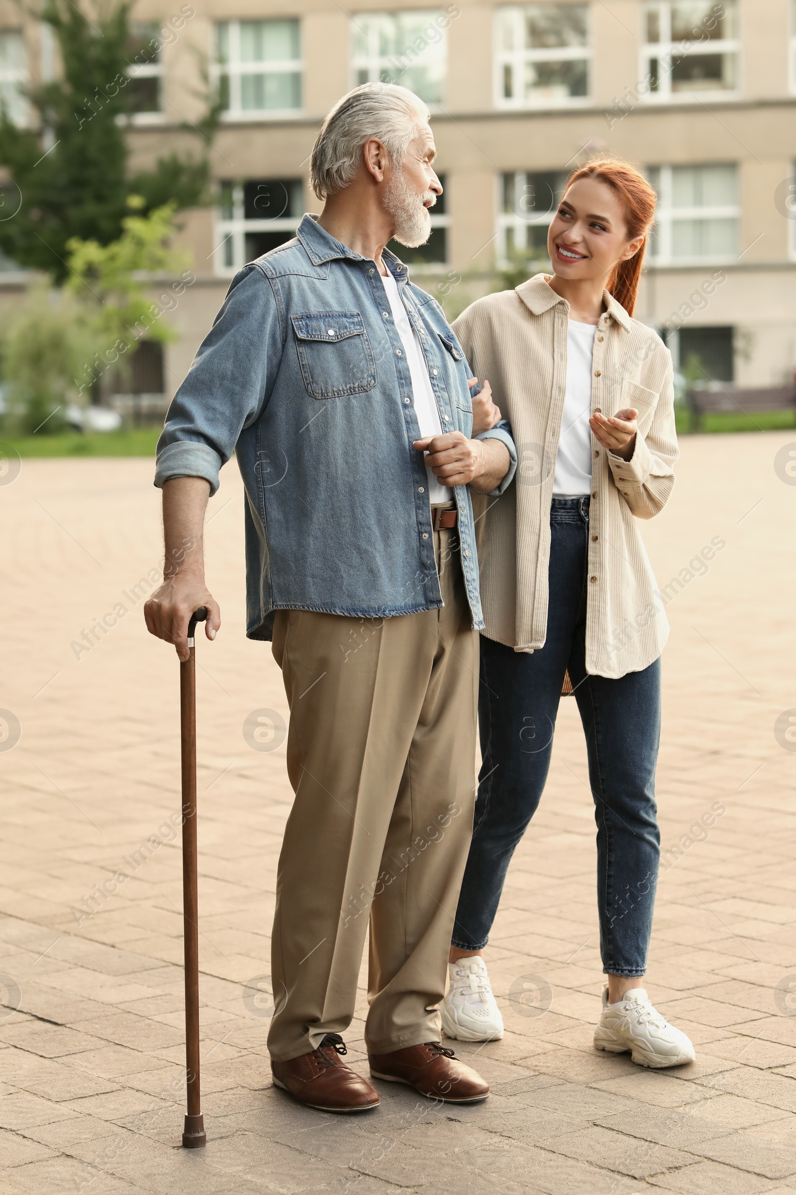 Photo of Senior man with walking cane and young woman outdoors