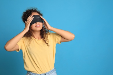 Photo of Young African-American woman with black blindfold on blue background