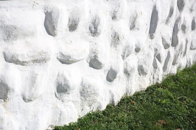 White stone wall of building near green grass outdoors. Exterior design