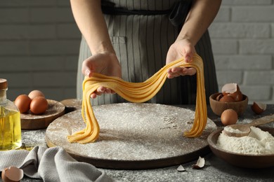 Photo of Woman making homemade pasta at table, closeup