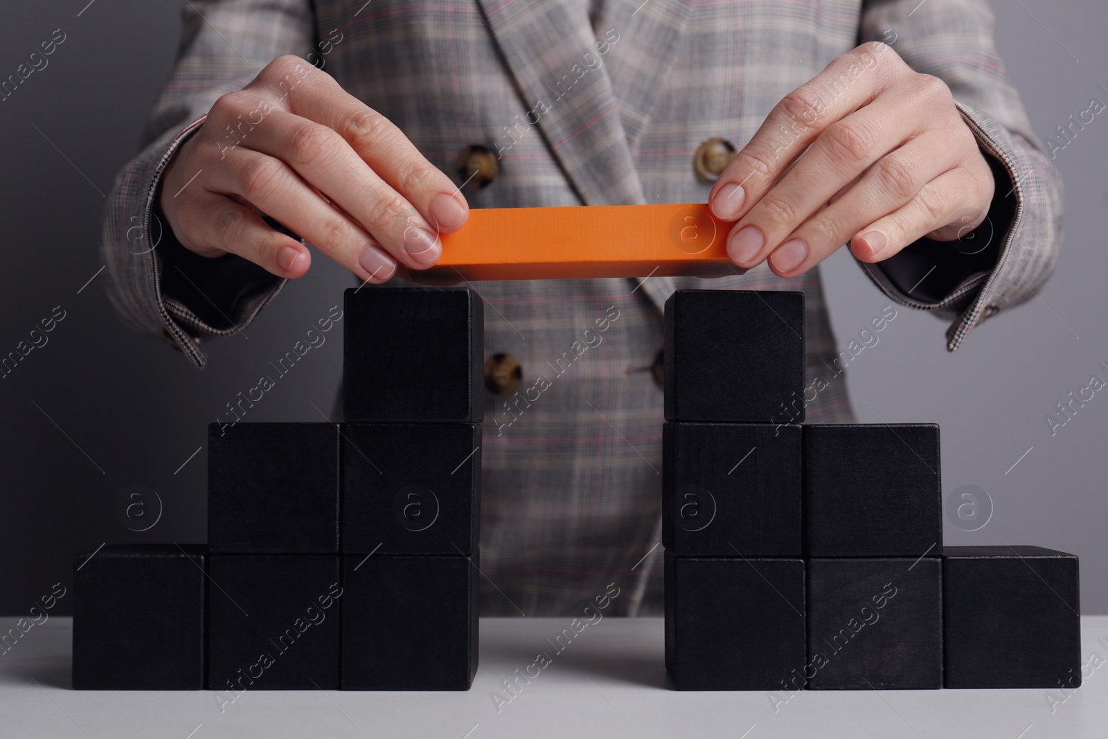 Photo of Businesswoman building bridge with colorful blocks at table, closeup. Connection, relationships and deal concept