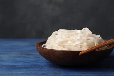 Photo of Bowl with rice noodles on wooden table. Space for text